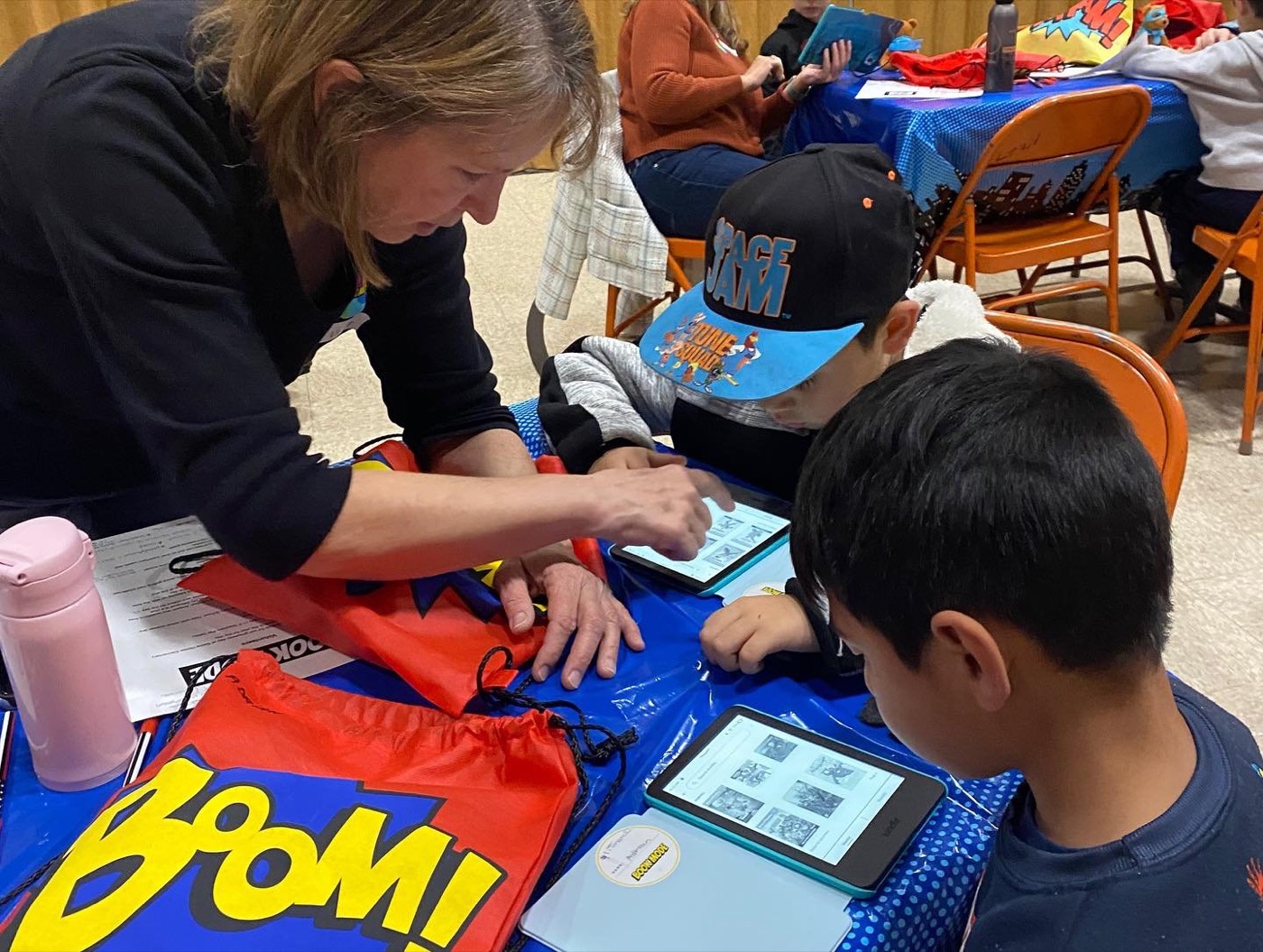 A boy in a superhero cape reading on his Kindle