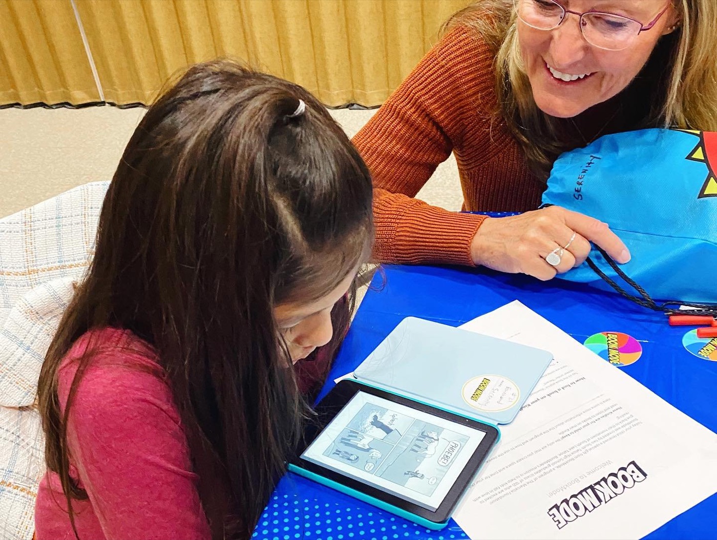 A girl and a teacher looking at her new Kindle together